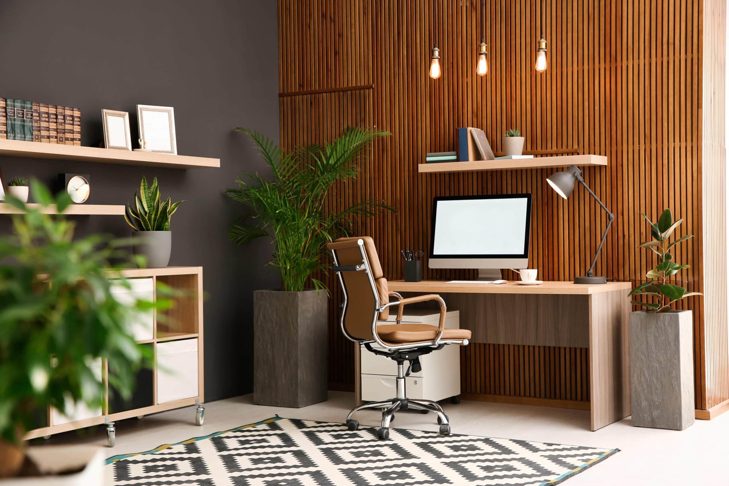 Bequemer Arbeitsplatz mit Computer in der Nähe einer Holzwand in einem stilvollen Rauminterieur. Design des Homeoffice